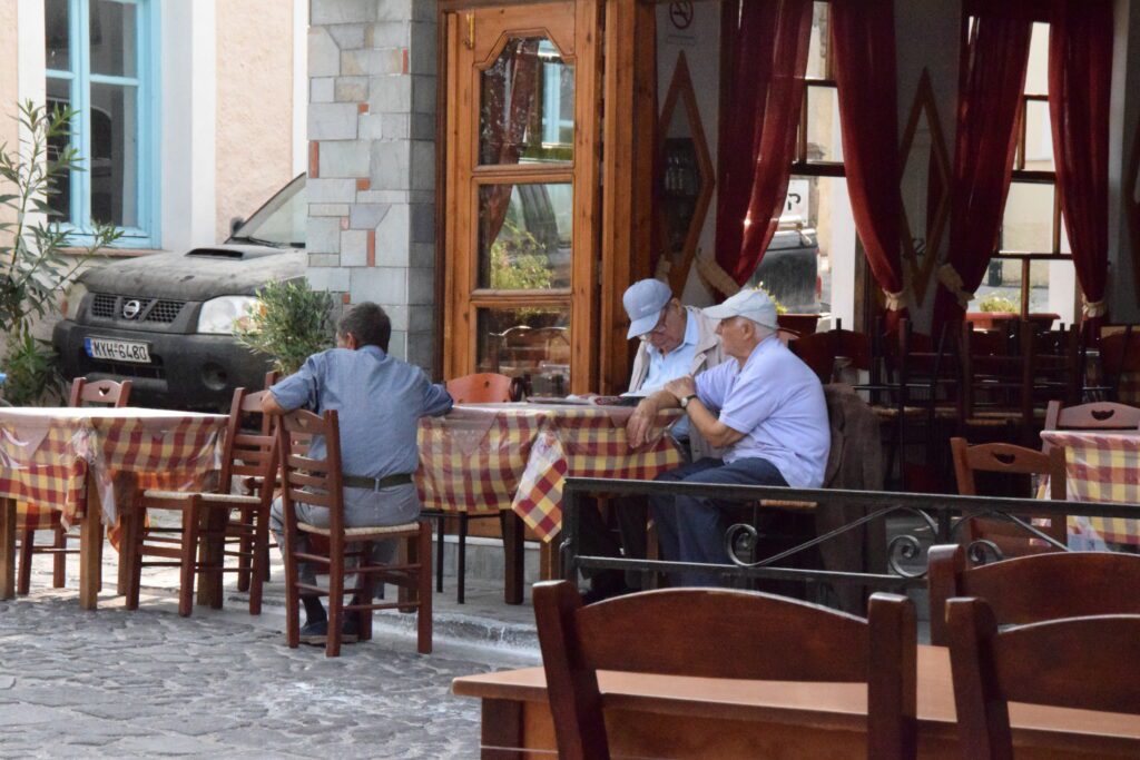 Griechische Kommunikation - Typische Szene in einem Kafenion, in dem ältere griechische Männer den Tag mit einem Ouzo und Elliniko verbringen