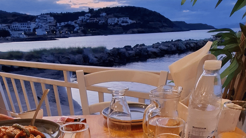 authentisch griechisch essen - An einem Tisch in einer griechischen Taverne sitzen mit Blick auf das Meer.